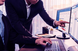 Profesionales de negocios analizan gráficos de barras y diagramas de Gantt en una pantalla de computadora para planificar proyectos de TI estratégicos