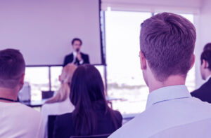 Asistentes en un auditorio escuchando a un expositor durante un seminario empresarial