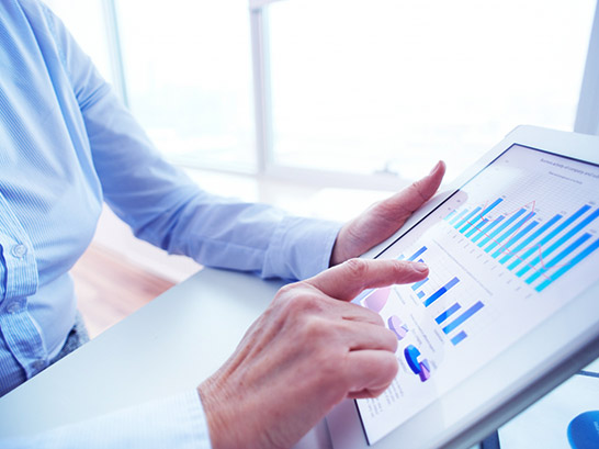 Primer plano de una profesional de negocios analizando gráficos de rendimiento y métricas en una tableta digital