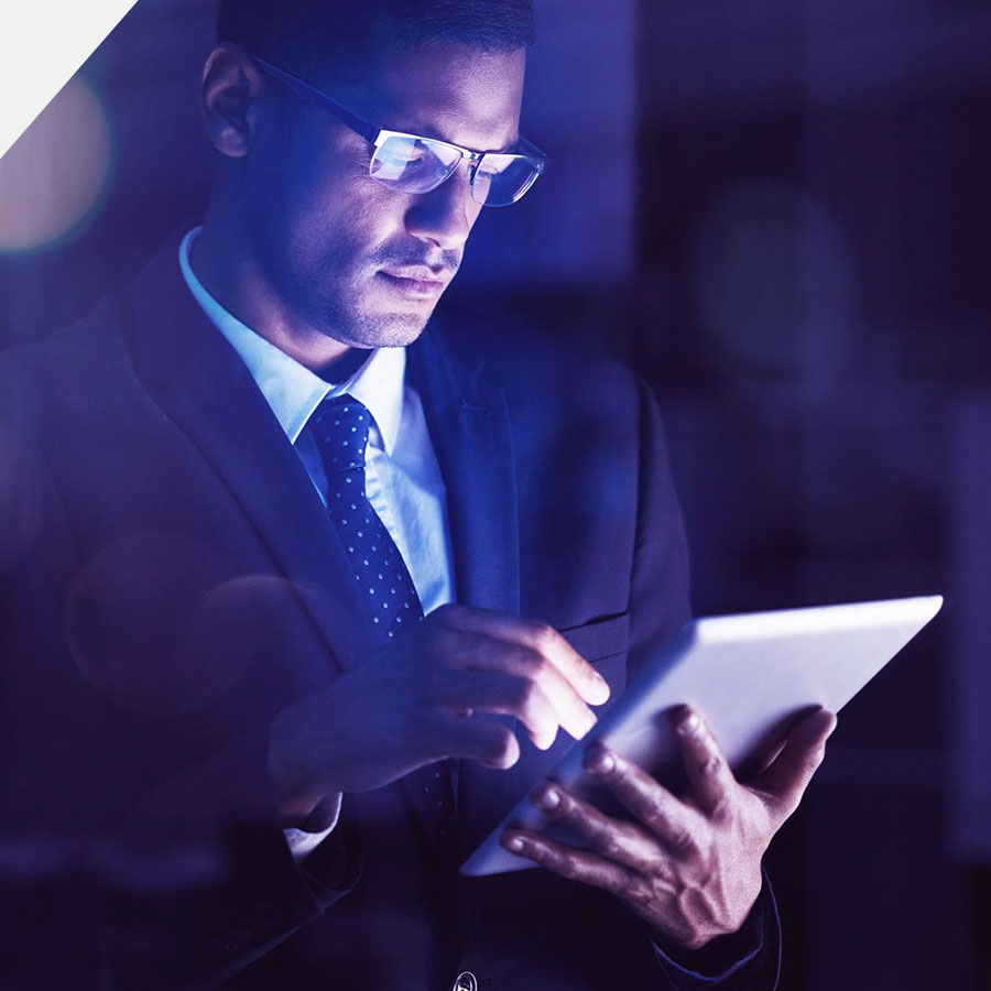Ejecutivo de negocios concentrado usando una tableta digital con iluminación azul tecnológica de fondo
