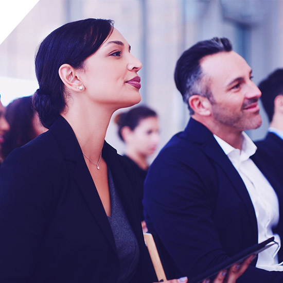 Profesionales de negocios atentos y sonrientes durante una presentación en una conferencia corporativa