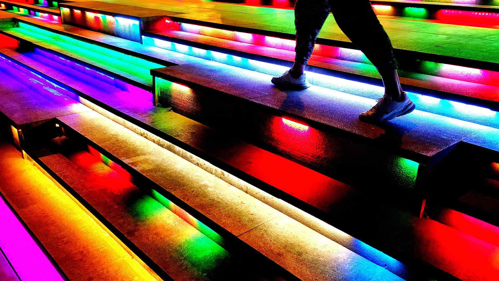Persona subiendo peldaños iluminados, representando el avance progresivo en la gestión del cambio organizacional